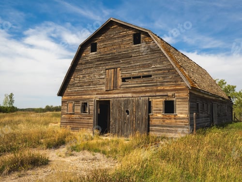 Preview: Old wooden barn in a rural field under a blue sky, showcasing rustic architecture and nature.