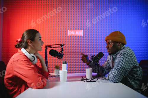 Preview: two radio hosts in headphones laughing while recording podcast in studio together