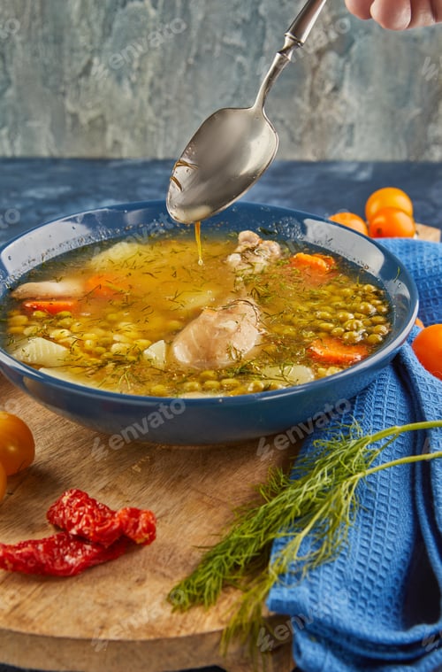 Preview: Pea soup with chicken, carrots, tomatoes and herbs in a deep plate on wooden board