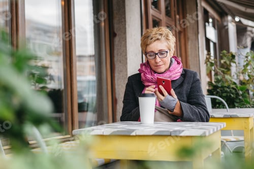 Preview: Woman Using Phone While Sitting at Outdoor Cafe
