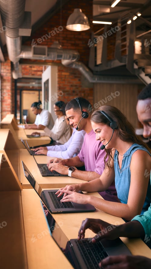 Preview: Multi-Cultural Customer Support Or Telesales Team In Modern Open Plan Office Wearing Headsets