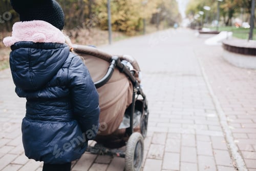 Preview: Child Pushing Stroller Along Walkway Outdoors