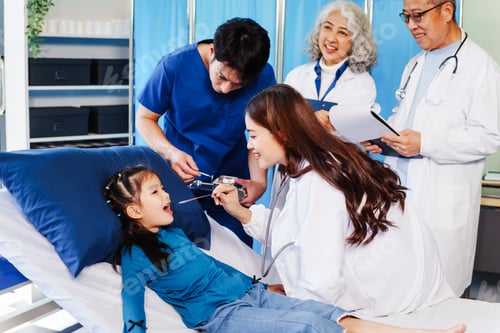 Preview: A doctor listens to a little girl’s heartbeat with stethoscope while she lies on a bed in hospital