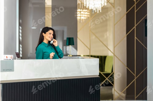 Preview: Portrait of female receptionist working at reception desk in hotel lobby.