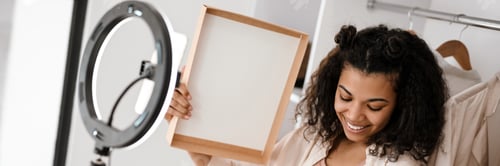 Preview: Happy young acrican woman influencer unpacking parcel