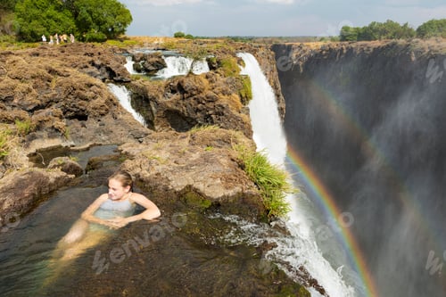Preview: Teenage girl in the water at the Devils Pool, on the cliff top overlooking Victoria Falls, Zambia.