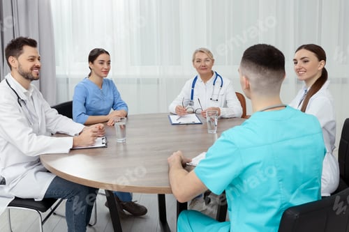 Preview: Medical conference. Team of doctors having discussion at wooden table in clinic