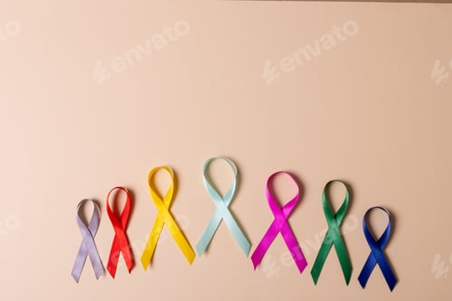 Preview: Directly above shot of various multicolored awareness ribbons arranged against peach background
