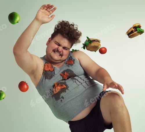 Preview: Dodge temptation - stick to your diet. Shot of an overweight man dodging food being thrown at him.
