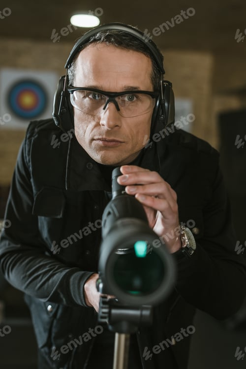 Preview: handsome man with binoculars in shooting range