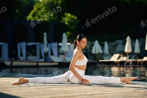 Preview: Sitting on twine. Woman near pool is doing yoga exercises