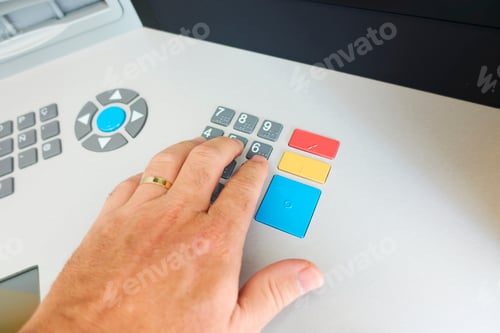 Preview: the hand of an unrecognizable person typing the secret pin code in an ATM to withdraw cash