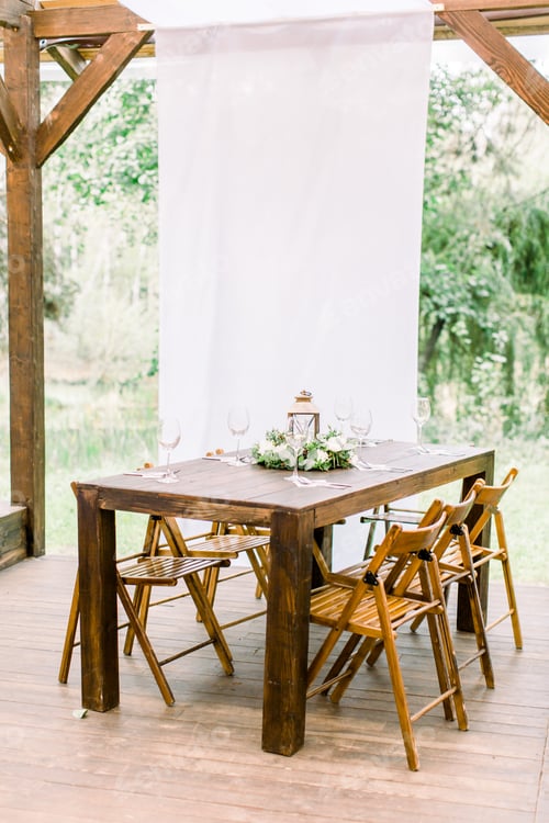 Preview: Wedding. Banquet. The wooden chairs and table for guests, decorated with flowers and greenery