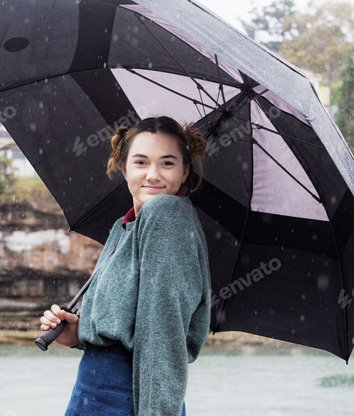 Preview: Teenage girl posing under an umbrella in the rain