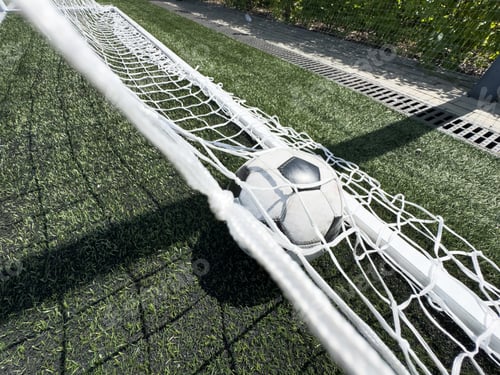 Preview: Soccer football in Goal net with green grass field. For sport concept.