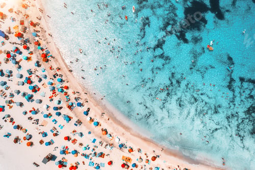Preview: Aerial view of sandy beach with umbrellas and sea at sunset
