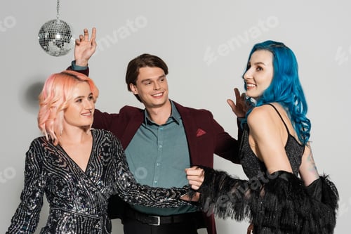 Preview: excited and stylish queer people dancing at christmas party on grey background