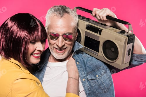 Preview: portrait of smiling woman hugging man with tape recorder isolated on pink