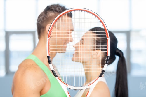 Preview: Fitness couple. Loving couple kissing behind tennis racket