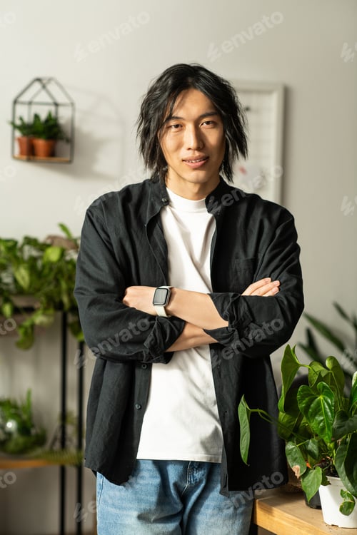 Preview: Young florist showcasing his craft amidst lush greenery in a cozy workshop setting