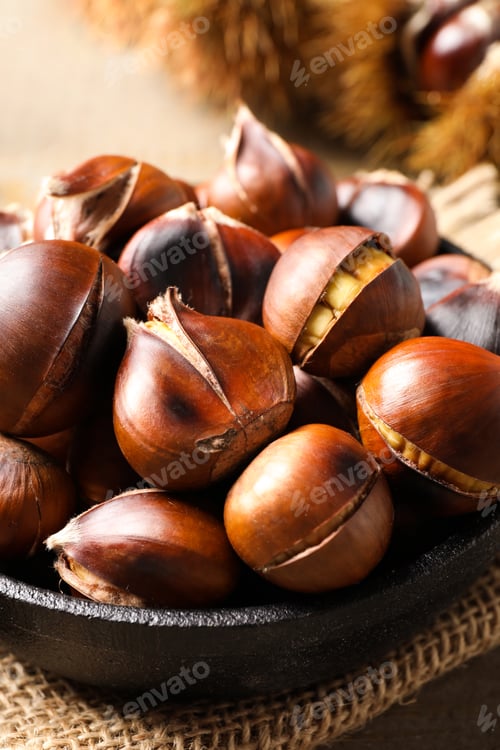Preview: Tasty roasted edible chestnuts on table, closeup