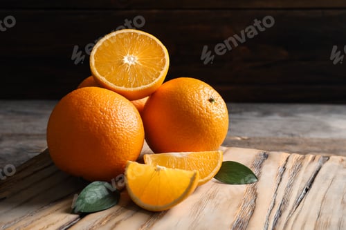 Preview: Fresh oranges with leaves on wooden table, space for text