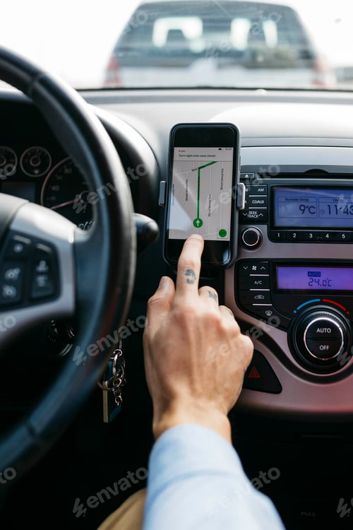 Preview: Close-up of man with tattooed hand driving car using cell phone as navigation system