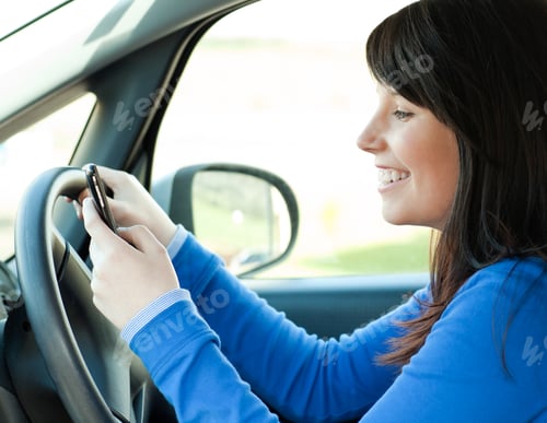 Preview: Brunette Young Woman Sending A Message With Her Mobile Phone Sitting In Her Car