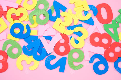 Preview: Top view of the colorful wooden numbers scattered on a pink surface