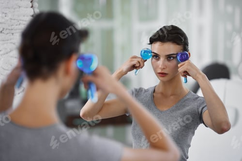 Preview: Facial skin care. A woman is doing a face massage using ice spheres.