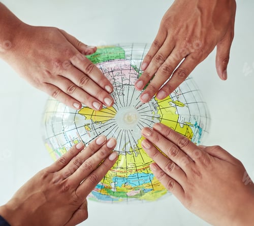 Preview: High angle shot of a group of unrecognisable people with their hands on a world globe