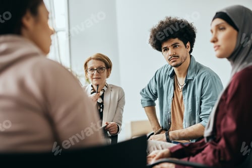Preview: Young Muslim man and group therapy members having counseling at mental health center.