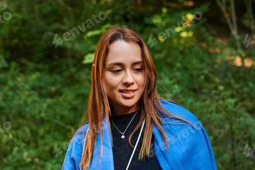 Preview: Hispanic woman smiling and looking down with trees in the background