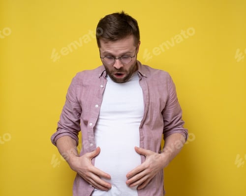 Preview: Man is shocked by his overweight, he looks at the excess fat on stomach and holds it with hands