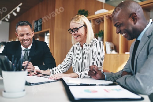 Preview: Three businesspeople laughing while working together at an office table