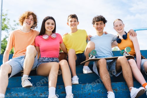 Preview: Smiling friends, teenagers in colorful t shirts hugging and looking at camera on street
