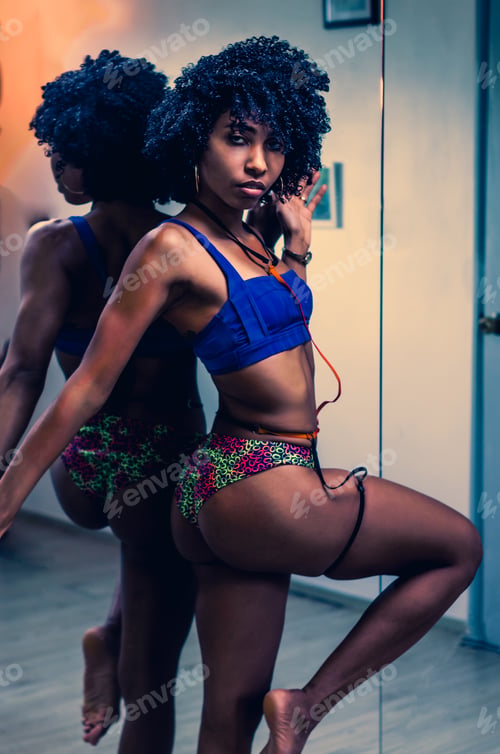 Preview: Latin Dominican woman posing for portrait, with afro hair and fitness body in front of mirror