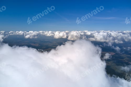 Preview: Aerial view from airplane window at high altitude of earth covered with white puffy cumulus clouds