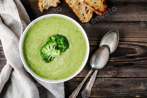 Preview: Homemade broccoli cream soup in white bowl with toasts on wooden background
