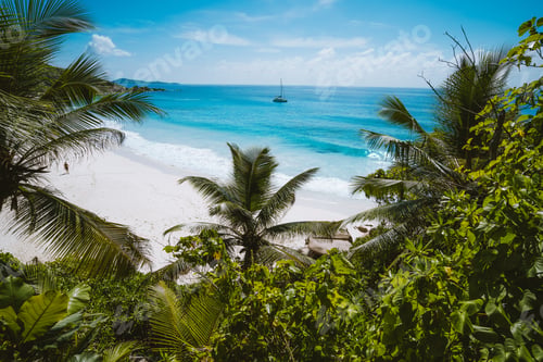 Preview: Holiday vacation at Petite Anse paradise beach framed by green foliage. La Digue island, Seychelles