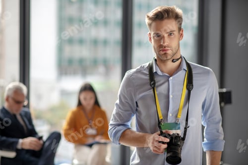 Preview: Young man in a blue shirt holding his camera