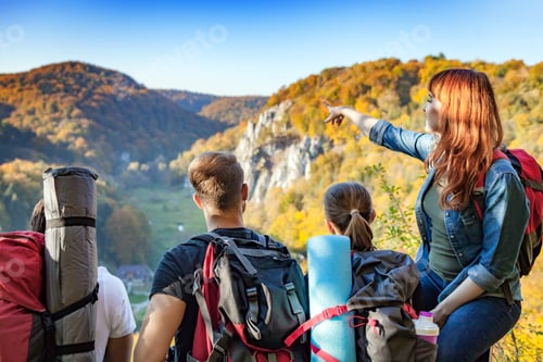 Preview: Group of people with backpacks looking at beautiful landscape view in the mountain