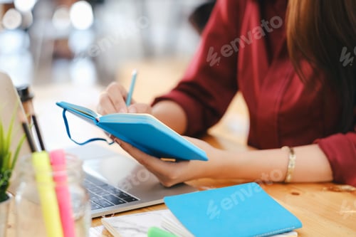 Preview: Close up female hands with pen writing on notebook.