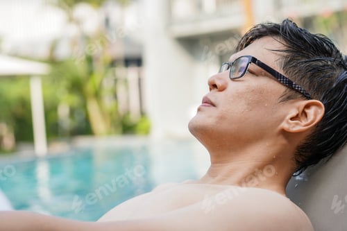 Preview: Asian man relax sitting by swimming pool