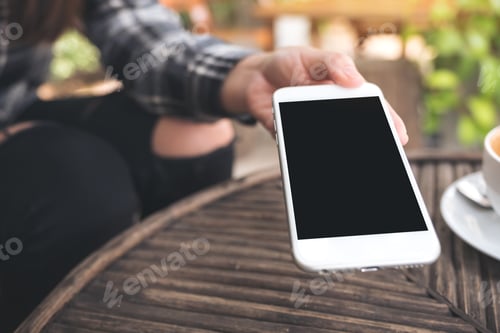 Preview: a hand holding and giving white mobile phone with blank black desktop screen to someone