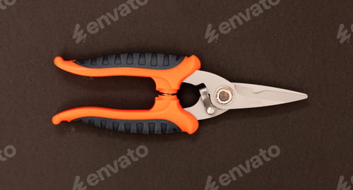 Preview: Sheet metal shears, scissors, steel point, orange, black color rubber handle on brown background.