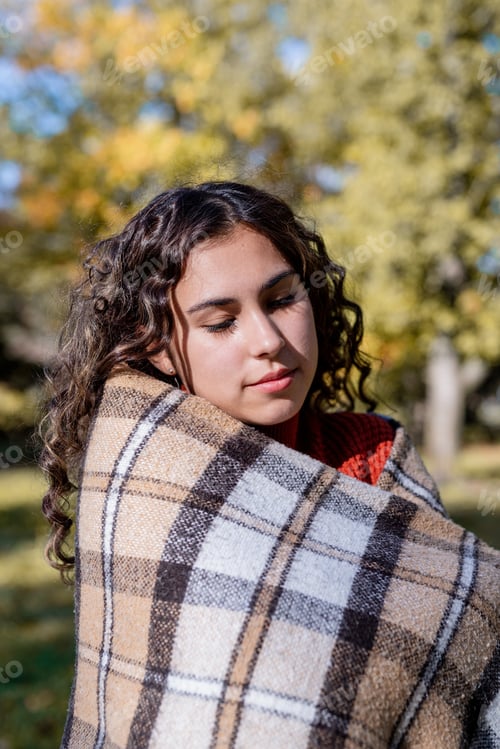 Preview: Portrait of young happy woman in warm plaid in autumn forest