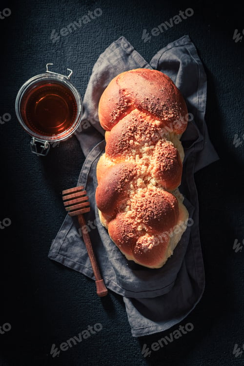 Preview: Healthy and homemade golden challah on dark table for breakfast.