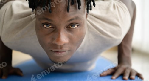 Preview: Young African man doing yoga exercise in the living room