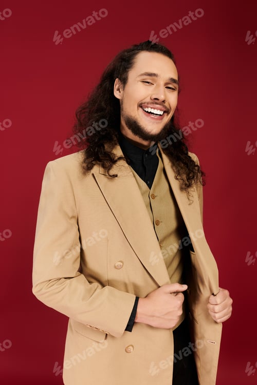 Preview: Handsome young bearded man smiles confidently against a striking red backdrop